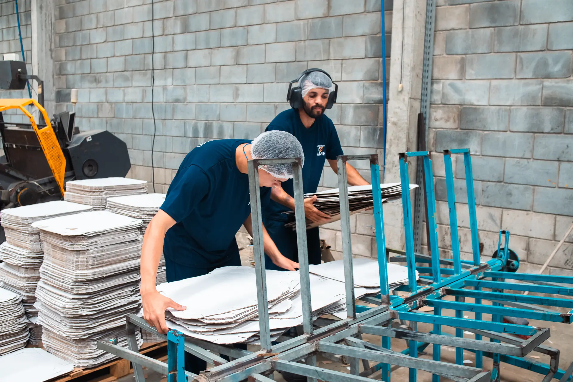 Equipe da AME organizando chapas de papelão na linha de produção