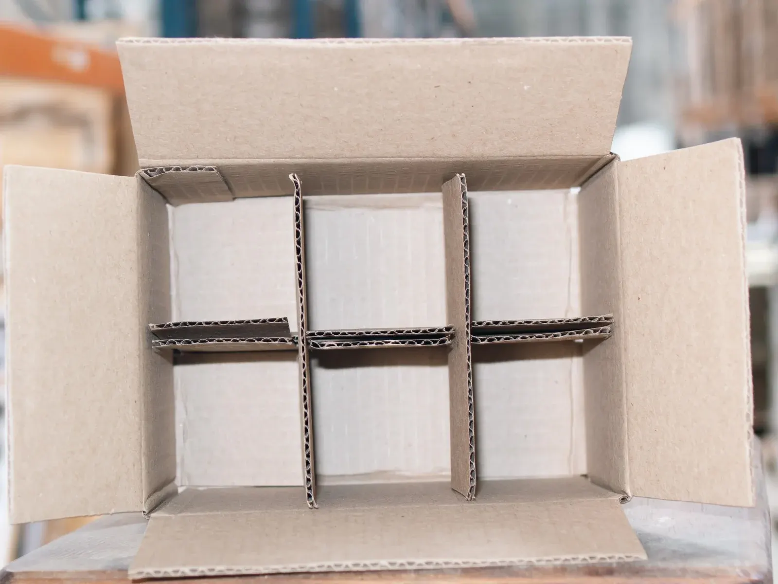 Interior de uma caixa baú com divisórias de papelão formando seis compartimentos